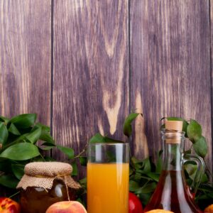 side view of fresh ripe peaches with muffin peach jam in a glass jar and peach juice in a glass on rustic wooden background Procesare produs dulceata