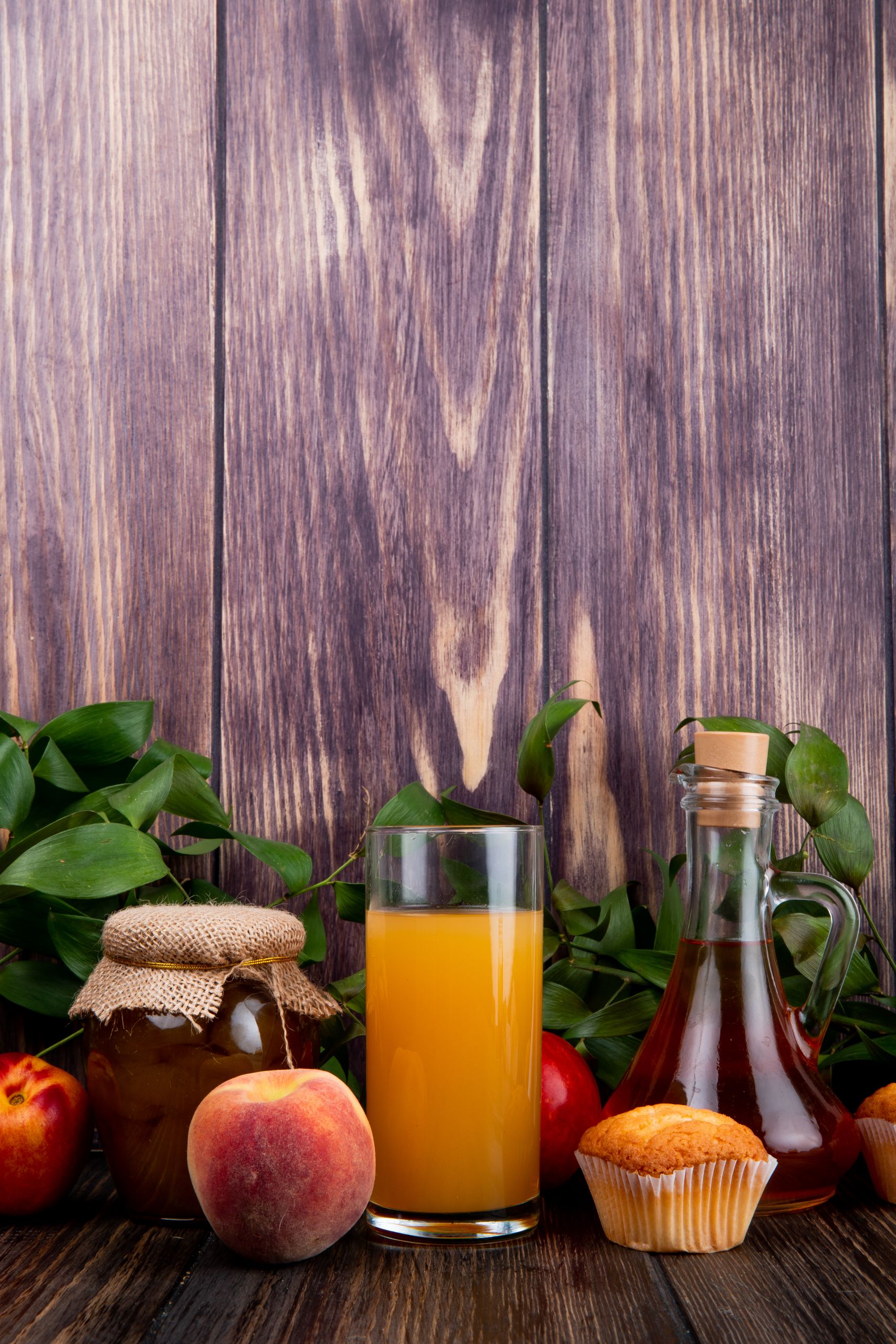 side view of fresh ripe peaches with muffin peach jam in a glass jar and peach juice in a glass on rustic wooden background Procesare produs dulceata